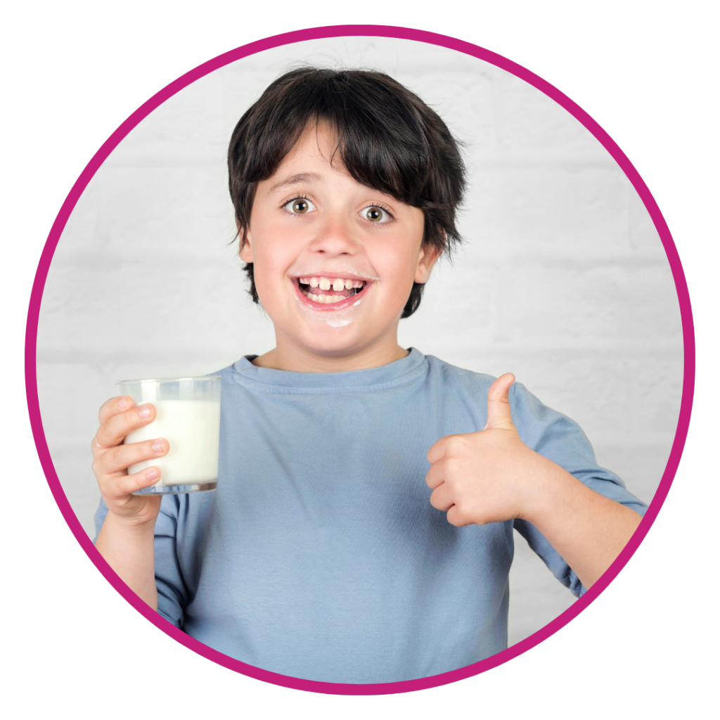Child in blue shirt holding glass of milk with thumbs up gesture