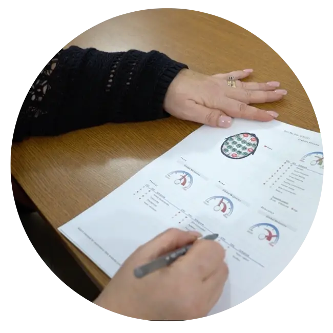 Hand holding document with QEEG brain map diagrams