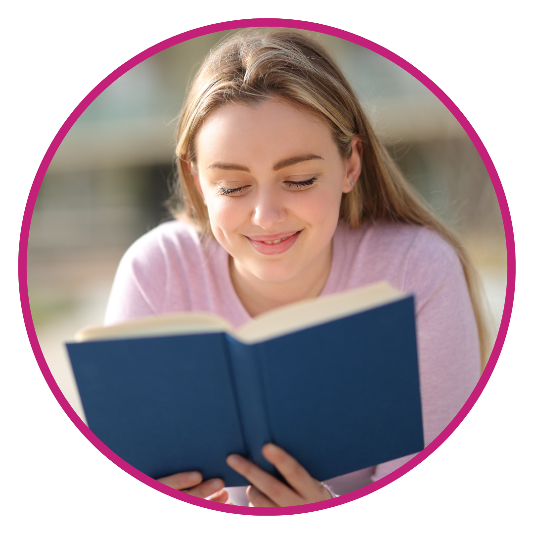 Teenage girl reading book outdoors in pink shirt