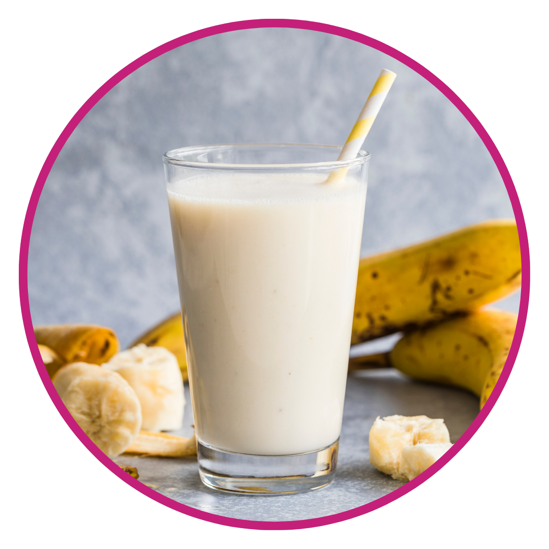 Glass of banana-flavored smoothie or milk beverage with bananas and straw