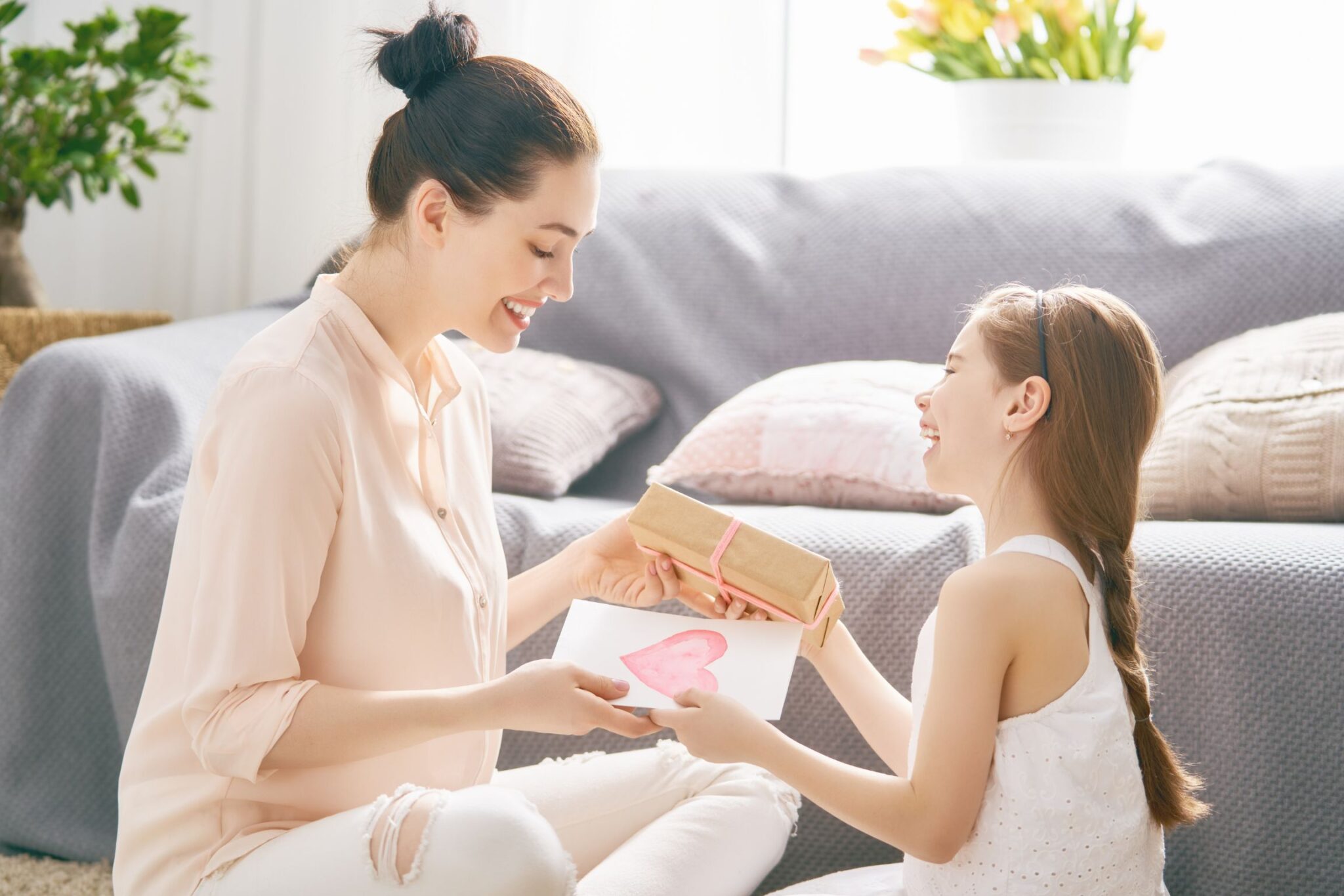 Mother and child exchanging wrapped gift on couch