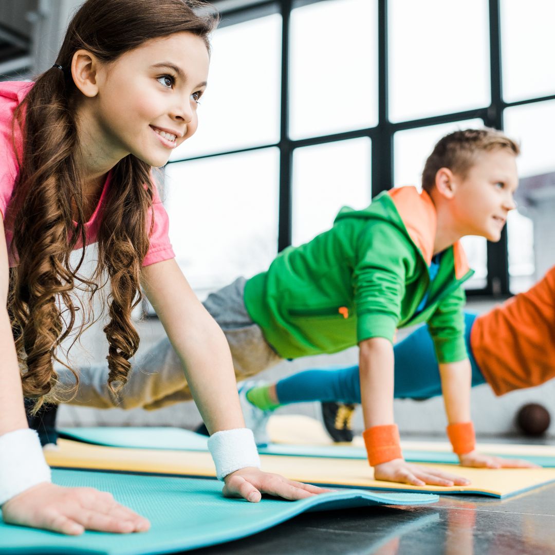 Children doing yoga stretches in fitness class