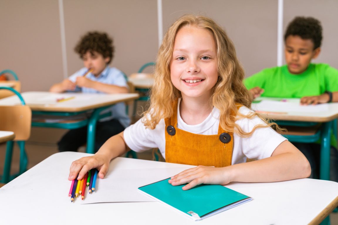 Student at classroom desk with colored pencils