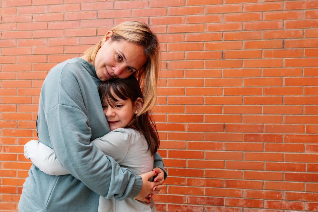 Woman embracing child against brick wall