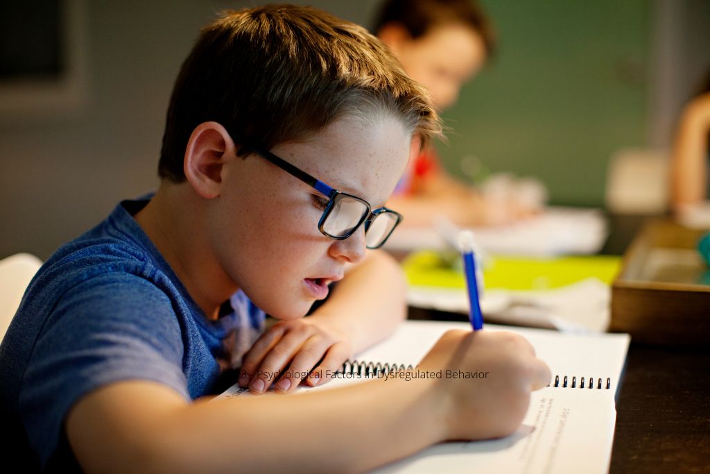 Child with glasses writing in notebook at desk