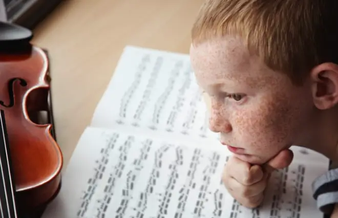 Boy reading sheet music while practicing violin