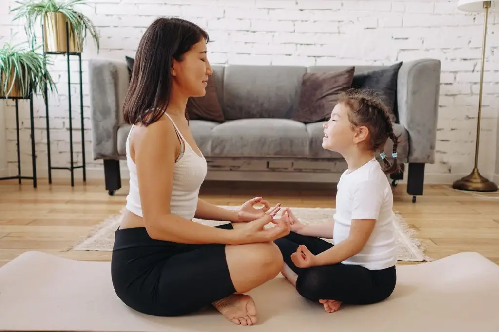 Adult and child sitting on a yoga mat at home doing a mindfulness activity together