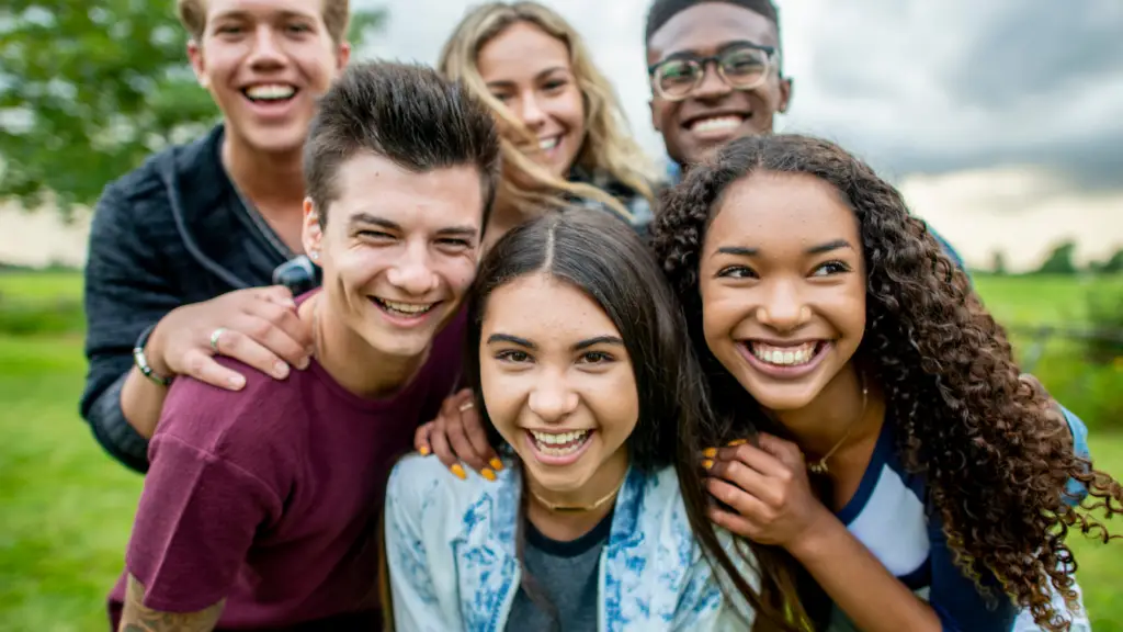 Group of diverse teens smiling and hugging together outdoors