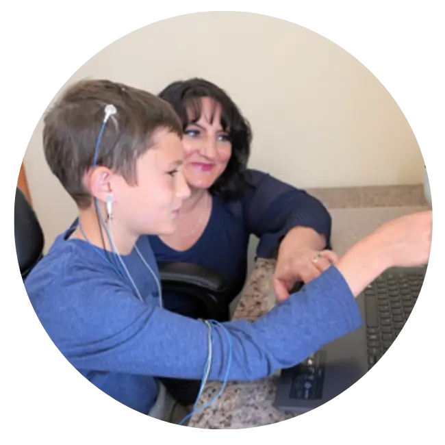 Adult and child engaged at desk with neurofeedback equipment