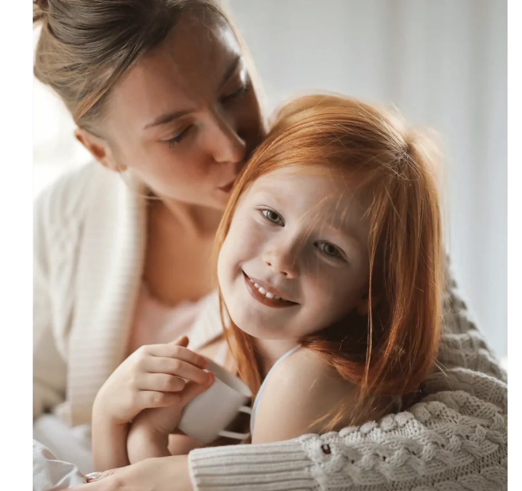 Mother leaning over her smiling redhead daughter showing affection and connection