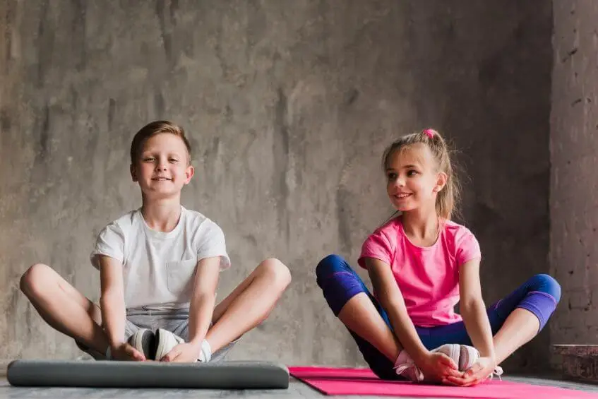 Two children stretching together on yoga exercise mats