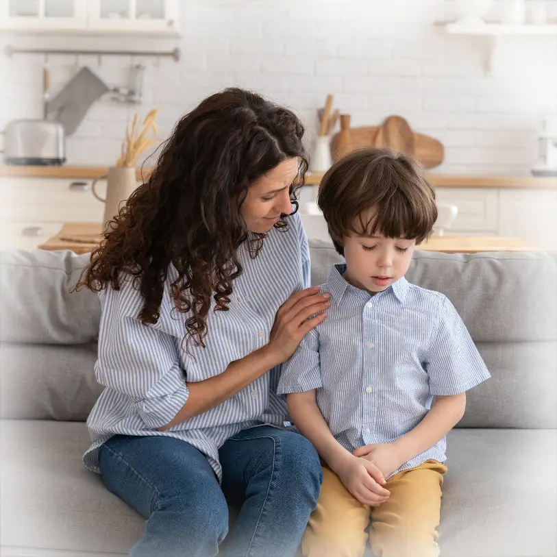 Mother with arm around child on couch at home