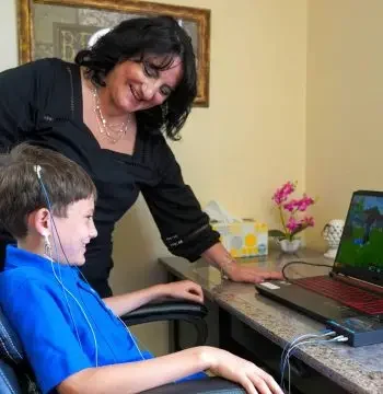 Dr. Roseann working with child at desk in clinical setting