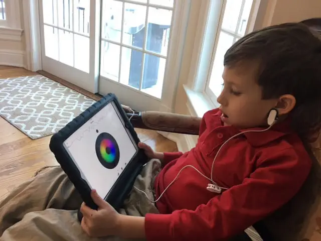Child holding tablet with colorful biofeedback circle on screen