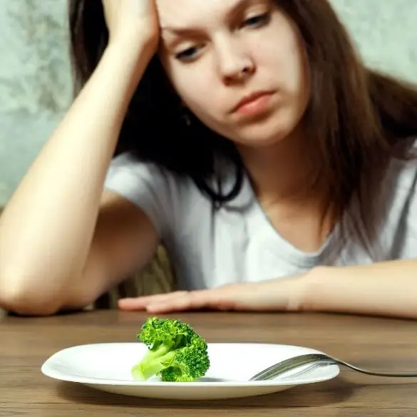 Teen girl looking concerned at table with small food portion