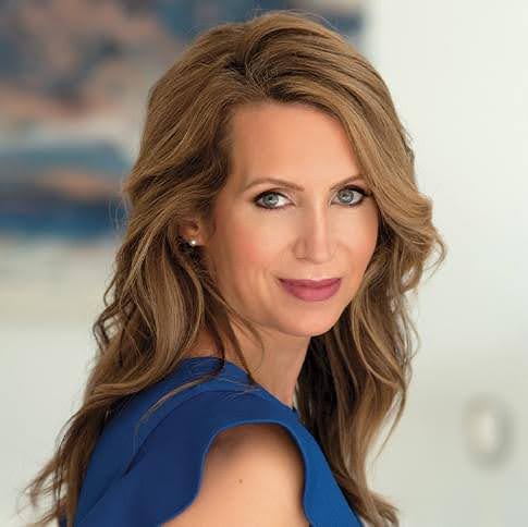 Woman with wavy brown hair wearing blue top, professional portrait